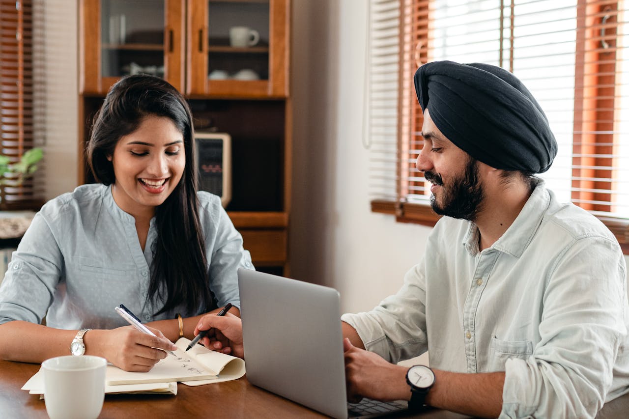 Happy Indian couple using laptop while doing homework together